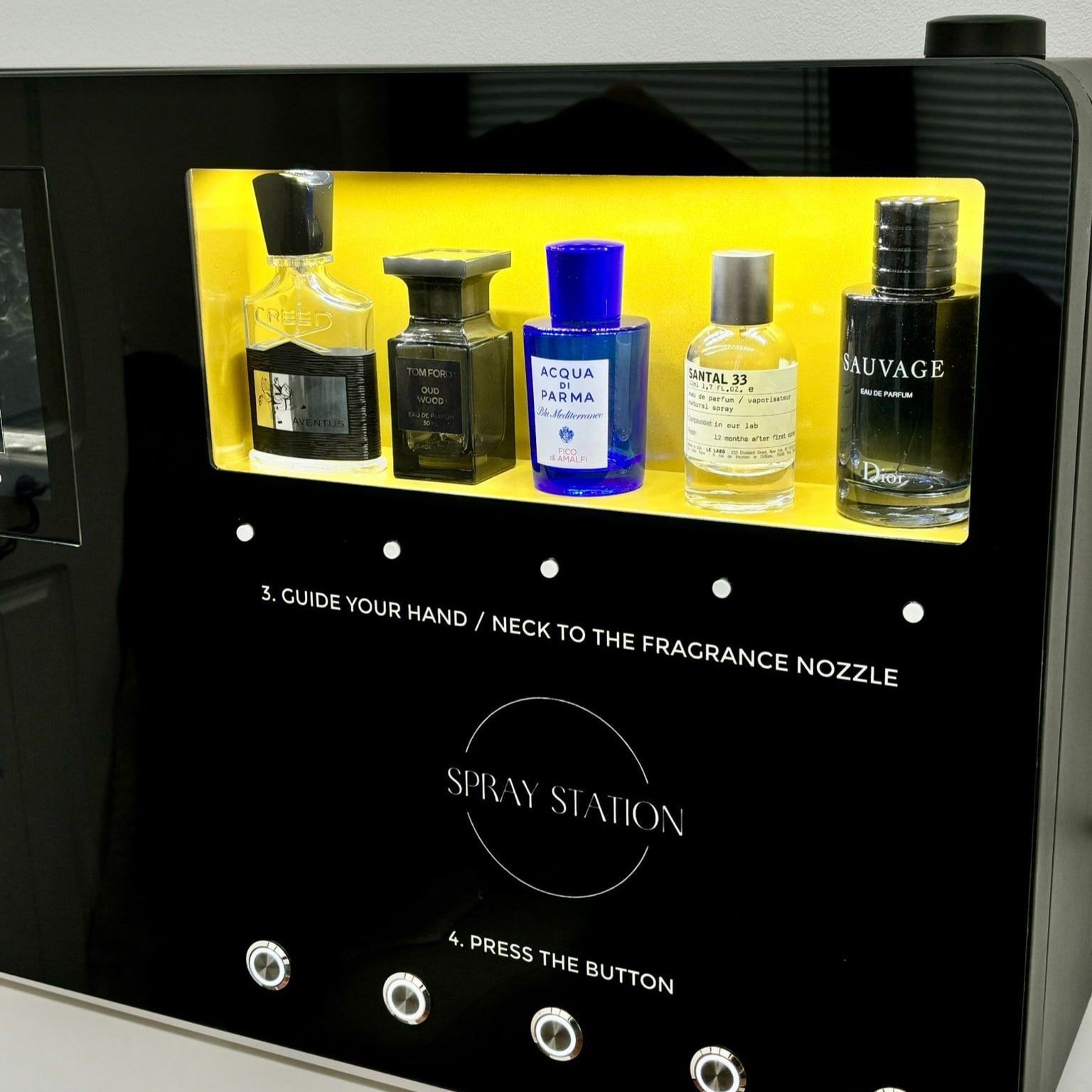 Perfume vending machine with an illuminated display of fragrance bottles