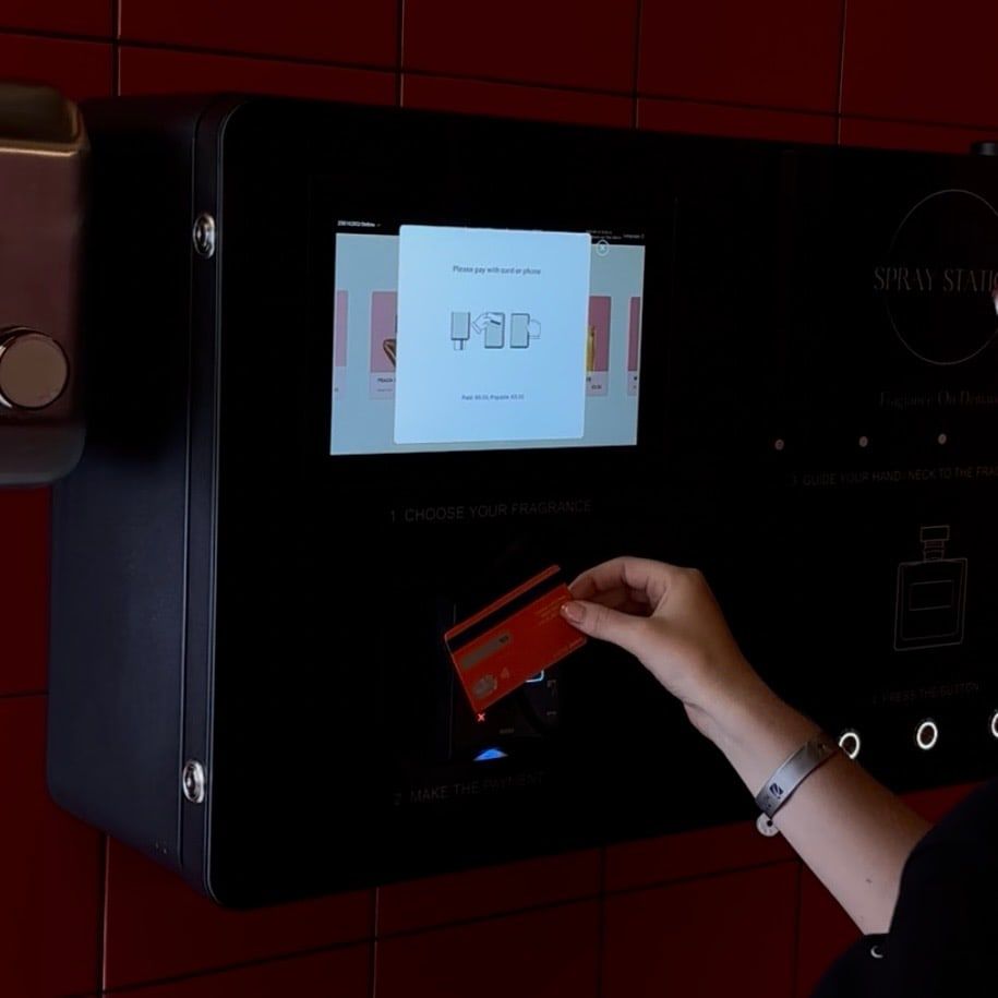 Guest paying contactlessly on a perfume vending machine